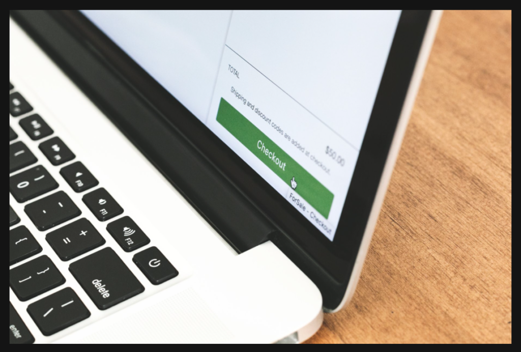 A laptop screen showing a green checkout icon.